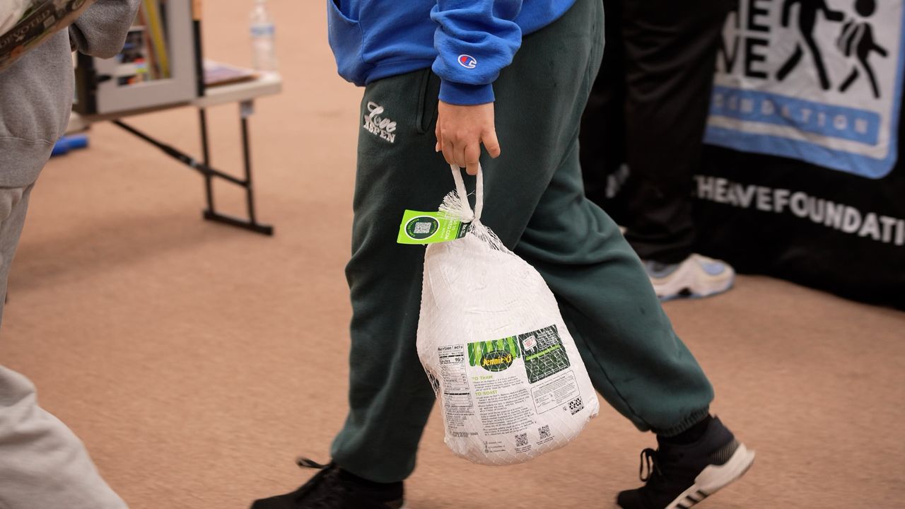 A person carrying a whole uncooked turkey.